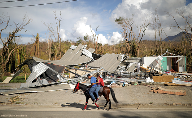 Locals ride a horse by a destroyed building in Jayuya, Puerto Rico, in October 2017, after Hurricane Maria 