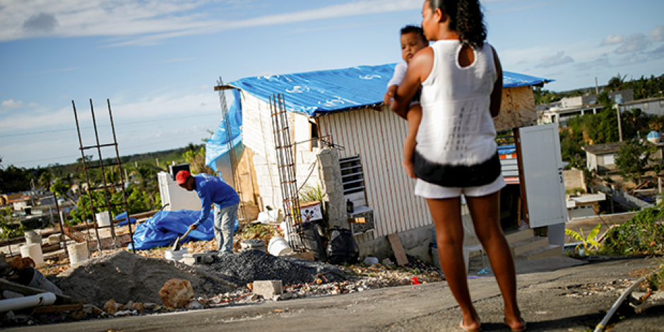 Samuel Vasquez rebuilds his house, which was partially destroyed by Hurricane Maria, while his wife Ysamar Figueroa looks on, whilst carrying their son